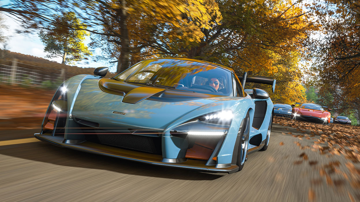 McLaren Senna разгоняется на дороге с растущими вдоль нее деревьями